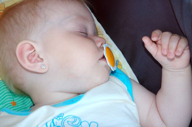 Baby girl asleep in stroller with orange pacifier