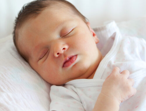 sleeping dark haired baby in infant swing