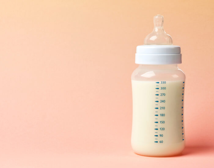 Baby Bottle on Table with Peach Background