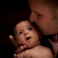 Father kissing his newborn baby