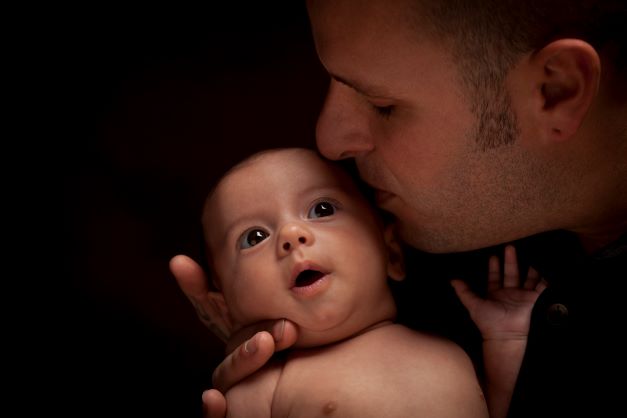 Father kissing his newborn baby