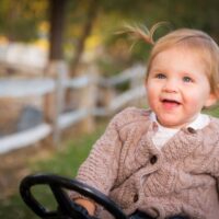 Happy toddler girl in sweater smiling and playing outside