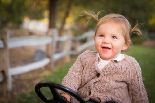 Happy toddler girl in sweater smiling and playing outside