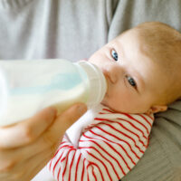 Parent feeding baby a bottle of formula