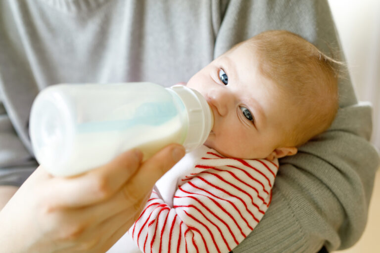 Parent feeding baby a bottle of formula