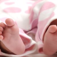 Close up of baby feet sticking out from a pink blanket