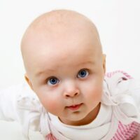 Close up of blue eyed infant girl on belly