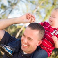 Happy father with happy toddler on shoulder