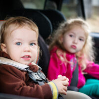 two toddlers sitting in car seats in vehicle