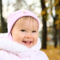 Little toddler girl outdoors in pink hat and coat