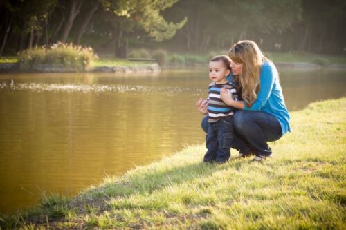 Mom and toddler boy looking together at water outdoors