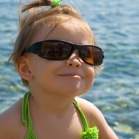 Happy toddler girl in sunglasses at the beach