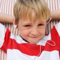 Little boy in red and white shirt listening to ear phones