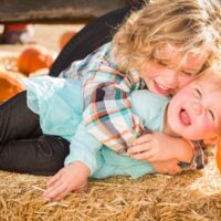 Little toddler and baby siblings at pumpkin patch