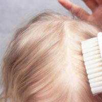 brushing top of baby's hair with brush