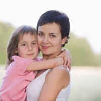 Mom with little girl hugging outisde