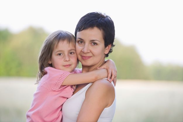 Mom with little girl hugging outisde