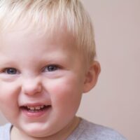 Blonde toddler boy wrinkling his nose