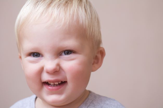 Blonde toddler boy wrinkling his nose