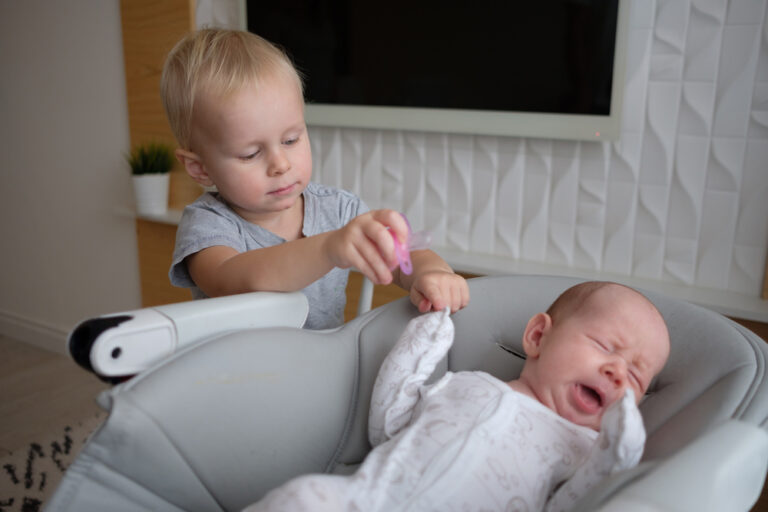 Big brother with baby who is in baby swing