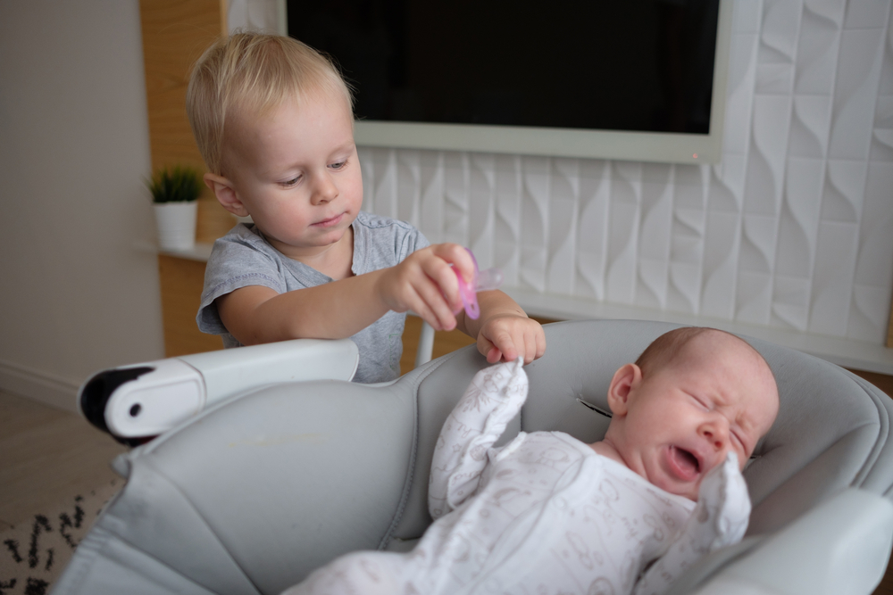 Big brother with baby who is in baby swing