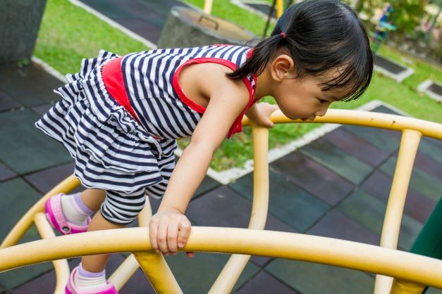 Little girl climbing outdoors at playground