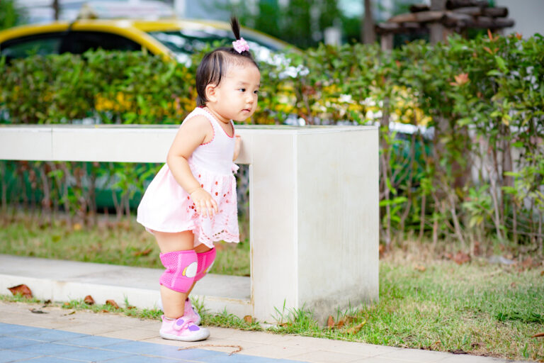 toddler on sidewalk wearing knee pads