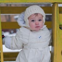 Baby girl playing at playground in cold and snow