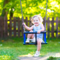 Laughing toddler in outdoor swing
