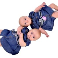 Twin baby girls laying together in denim dresses