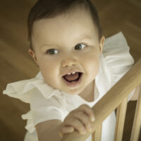 Smiling Girl Standing at Baby Gate