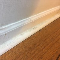 Dirty baseboard by wood floor