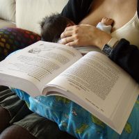 Picture of a baby breastfeeding while her mother is studying for graduate school