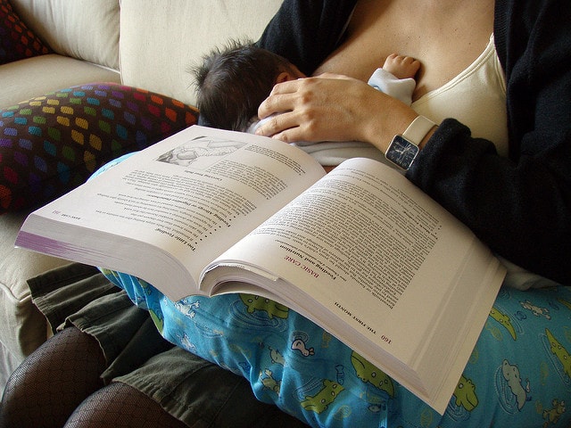 Picture of a baby breastfeeding while her mother is studying for graduate school