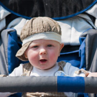 Adorable baby boy wearing a hat sitting in stroller