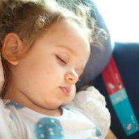 Closeup of little girl asleep in car seat