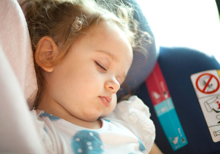 Closeup of little girl asleep in car seat