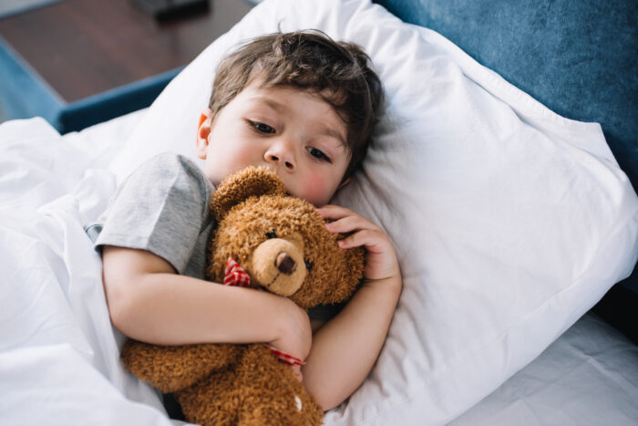 child laying on pillow with teddy bear