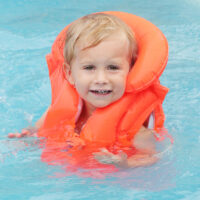 baby swimming in pool with life jacket on