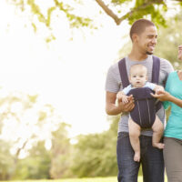 parents walking while dad wears baby in baby carrier