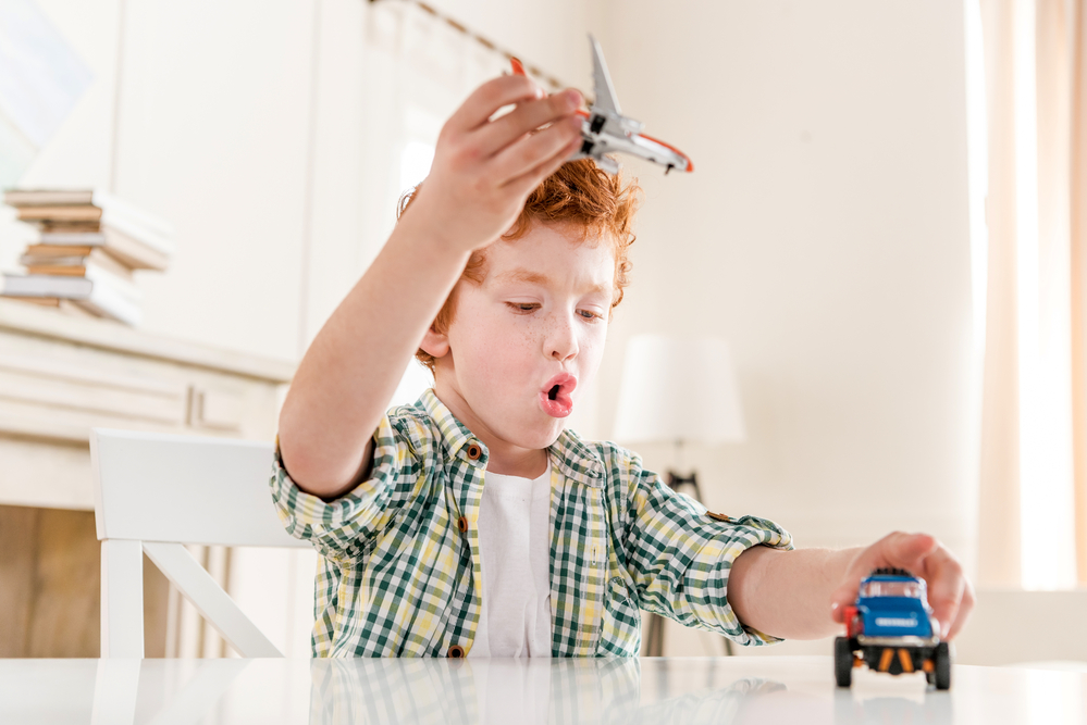 4 year old boy playing with toy airplane and toy car