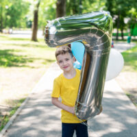 Little boy in yellow shirt with #7 balloon