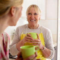 Mom and Older Daughter Drinking Coffee Together in Kitchen