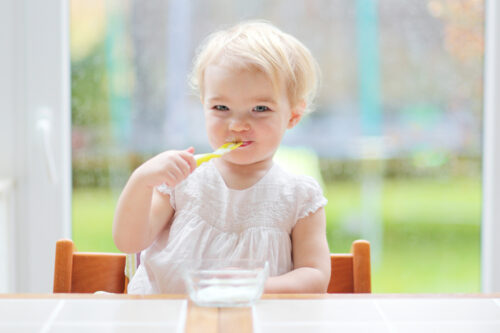 baby eating yogurt at the table