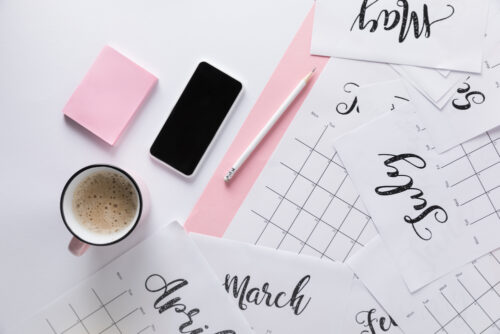 Calendar laying across desk with coffee and pen