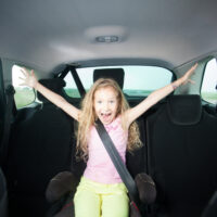 Curly haired girl happy in booster seat in car