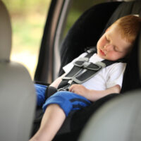 Little blonde boy asleep in car seat