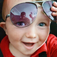 Smiling boy in car seat with sunglasses
