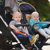 Two toddlers in stroller side by side