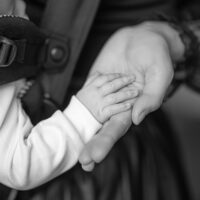 Mom and baby holding hands in baby carrier